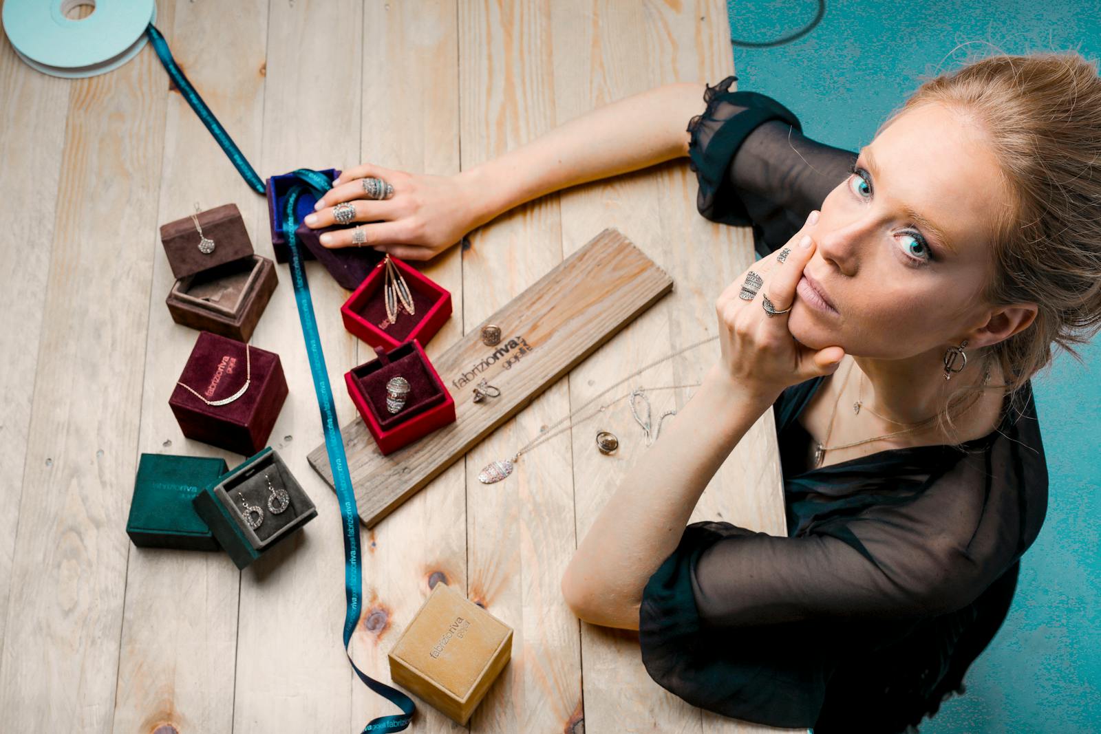 general liability From above serious businesswoman looking up at camera while sitting at wooden table with small jewelry boxes with bijouterie and decorating with ribbon as present